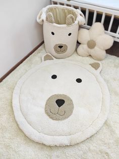 a teddy bear rug next to a crib with a stuffed animal in the corner