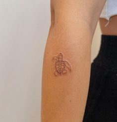 a small turtle tattoo on the left arm