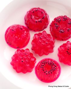 five red candies on a white plate with black dots in the middle and one is cut into smaller pieces