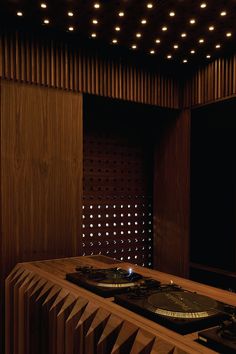 two turntables sit on top of a wooden table in front of a wood paneled wall