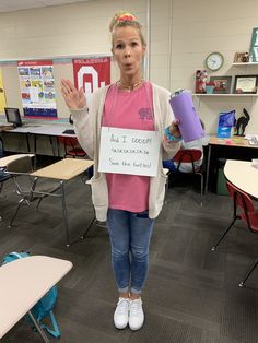 a woman standing in a classroom holding a sign