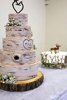 two wedding cakes are sitting on top of a table with white linens and wood slices