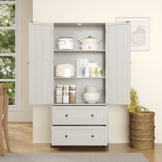 an open cabinet with dishes on it in a room next to a table and chairs