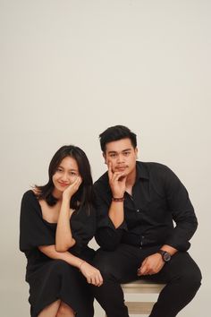 a man and woman sitting next to each other posing for a photo on a stool