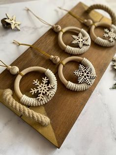 three wooden hoops with snowflakes hanging from them on a wood board next to christmas decorations