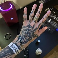 a person's hand with tattoos on it sitting in front of a computer keyboard