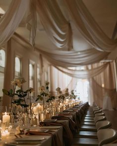 a long table is set with candles and flowers in vases on the tables, along with place settings