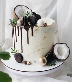 a white cake with chocolate drizzled on top and coconuts around it