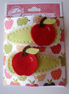 two red apples are sitting on top of a white card with green leaves and polka dots