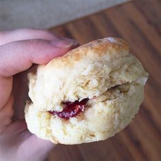 a hand holding a biscuit with jam on it