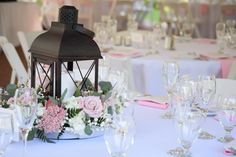 a lantern is on top of a table with white and pink flowers in the center