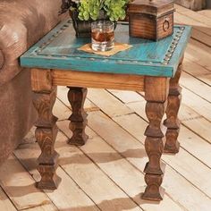 a wooden table with a glass on it and flowers in a vase sitting on top