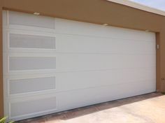 a white garage door in front of a tan building