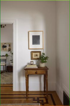 a wooden table sitting in the middle of a room next to a doorway with pictures on it