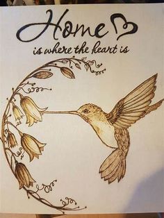 a drawing of a hummingbird in flight with the words home is where the heart is