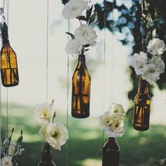 several bottles filled with flowers hanging from strings