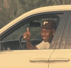 a man sitting in the driver's seat of a car pointing to the side