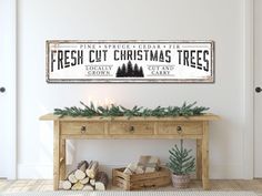 a wooden sign that says fresh cut christmas trees on the side of a table with candles