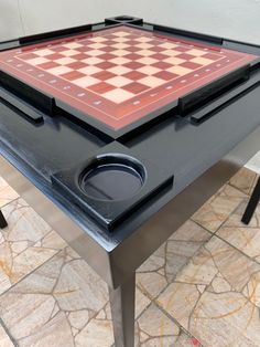 a black and red checkerboard table on top of a tile floor with metal legs