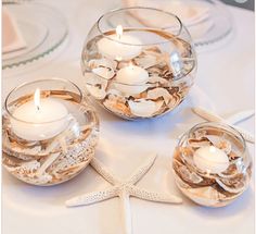 three glass bowls filled with candles on top of a table