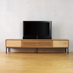 a television is sitting on top of a wooden stand in front of a white wall