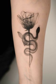 a black and white photo of a flower with a snake tattoo on it's arm