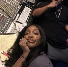 a woman laying on top of a desk next to a man with a microphone and keyboard