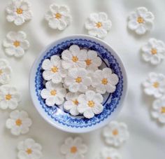 small white crocheted flowers in a blue and white bowl on a white tablecloth