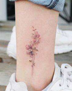 a woman's lower leg with a small flower tattoo on her left side ribcage