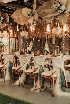 a room filled with lots of tables and chairs covered in white cloths next to flowers