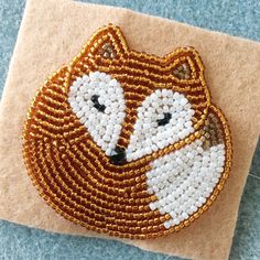 a beaded fox is sitting on top of a piece of fabric