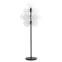 a floor lamp with five white balls on it's black base and an oval glass shade