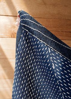 a person holding up a blue and white cloth on a wooden floor with wood planks in the background