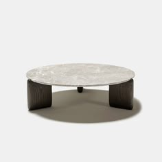 a round table with black legs and a white marble top, on a grey background