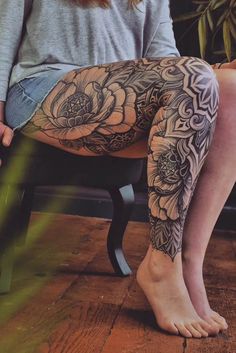 a woman is sitting on a chair with her legs crossed and tattoos on the leg