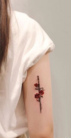 a woman with a cross tattoo on her arm and behind her is a red rose