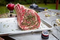 a piece of raw meat sitting on top of a metal tray next to a grill