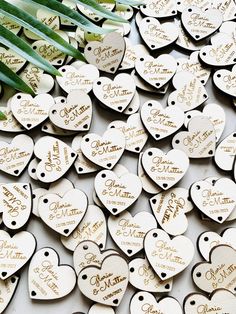 lots of wooden hearts with names and date written on them, surrounded by palm leaves