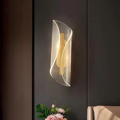 a vase with flowers on a table next to a wall light that is shaped like a wave