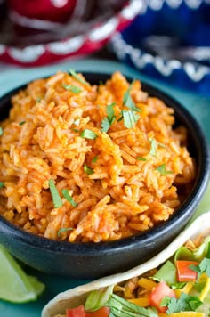 mexican rice in a black bowl with tortillas and cilantro on the side