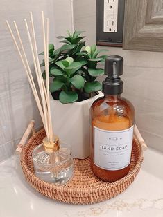 a bottle of liquid sitting on top of a bathroom sink next to a glass container with reeds