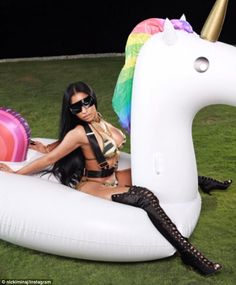 a woman sitting on top of an inflatable unicorn shaped pool floatie with a pink flamingo