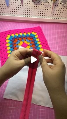 someone is making a crochet pattern on a piece of pink paper with scissors