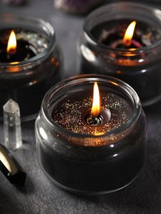 three lit candles sitting on top of a table next to some rocks and crystal sticks