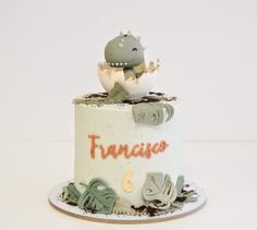 a birthday cake with an egg in the shape of a dinosaur on top and other animals around it