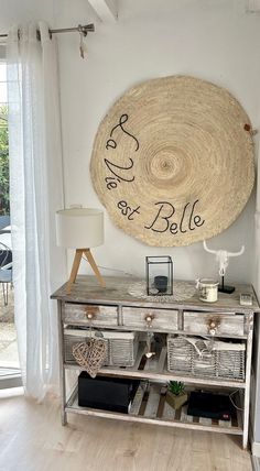 a table with baskets on it in front of a large round wall hanging above it