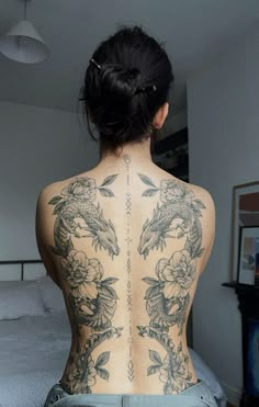 the back of a woman's body with tattoos on her upper and lower back