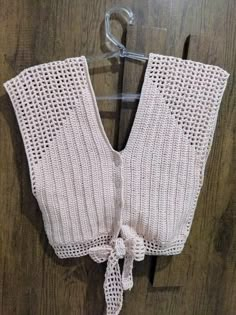 a white knitted sweater hanging on a hook