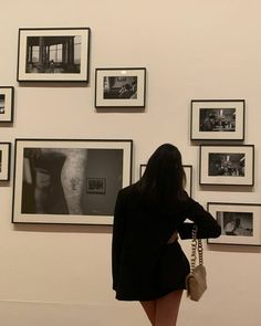 a woman is looking at pictures on the wall