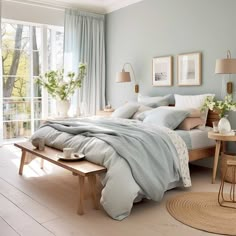 a bedroom with light blue walls and white furniture, including a bed covered in grey linens